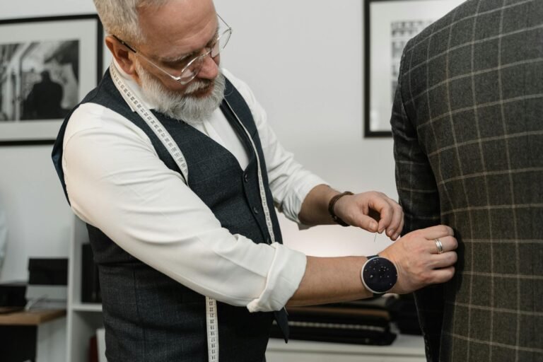 An experienced tailor meticulously adjusts a custom suit in a stylish atelier.