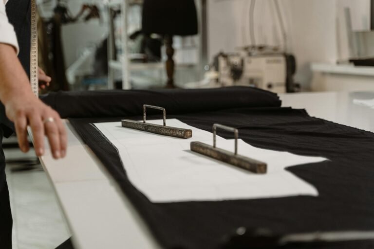 Close-up of a tailor measuring fabric with a tape in a sewing studio.